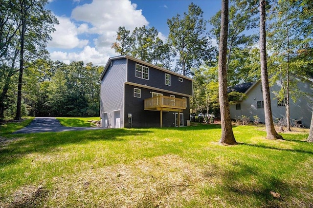 rear view of house featuring a garage, a yard, and a deck