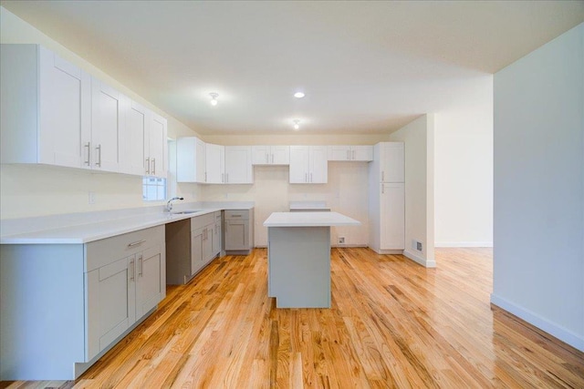 kitchen with a center island, sink, light hardwood / wood-style flooring, gray cabinets, and white cabinetry