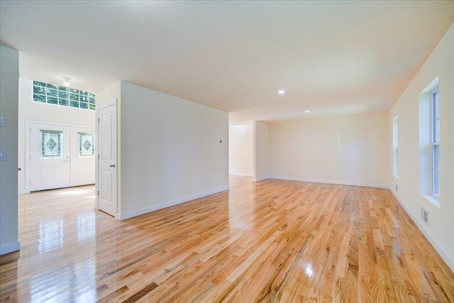 spare room with french doors and light hardwood / wood-style flooring