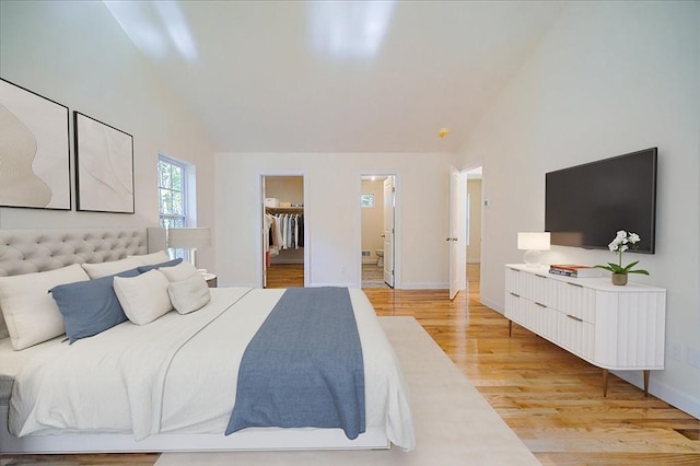 bedroom featuring high vaulted ceiling, light hardwood / wood-style flooring, a spacious closet, and a closet