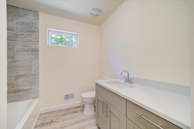 bathroom with hardwood / wood-style floors, vanity, a bathtub, and toilet