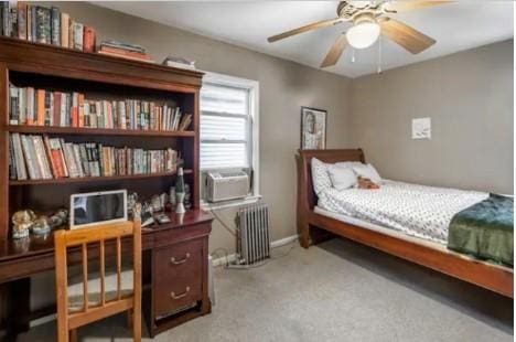 bedroom with carpet flooring, ceiling fan, cooling unit, and radiator heating unit