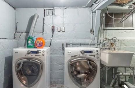 clothes washing area featuring washer and clothes dryer and sink