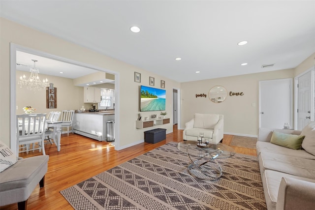 living room with a chandelier, hardwood / wood-style floors, and a baseboard radiator