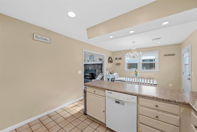 kitchen with dishwasher, pendant lighting, light tile patterned flooring, an inviting chandelier, and a stone fireplace