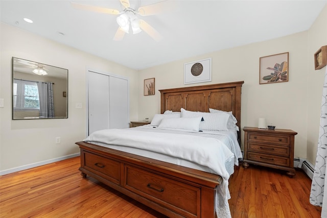 bedroom with ceiling fan, a closet, baseboard heating, and light hardwood / wood-style flooring