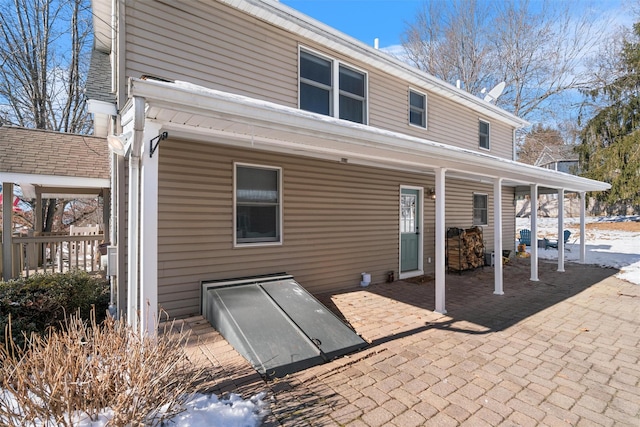 snow covered rear of property featuring a patio