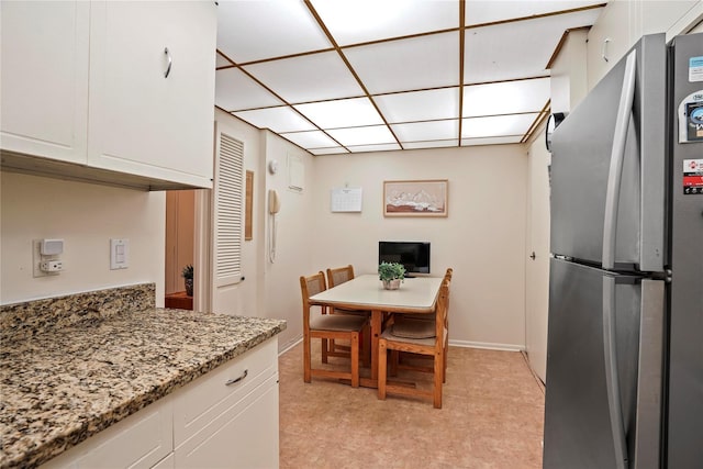 kitchen with white cabinetry, stone countertops, and stainless steel fridge