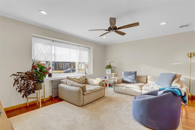 living room featuring hardwood / wood-style floors, ceiling fan, crown molding, and radiator