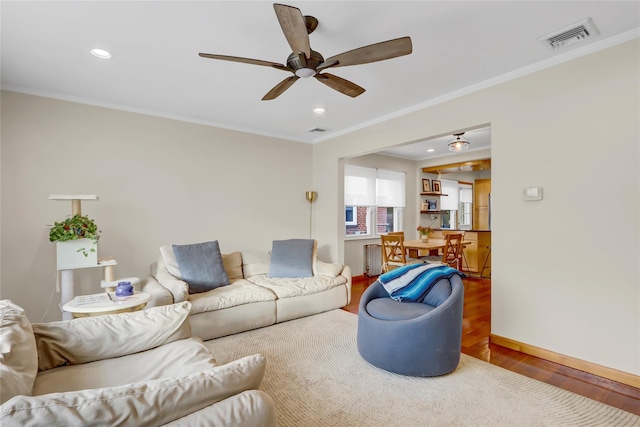 living room featuring ceiling fan, wood-type flooring, and ornamental molding