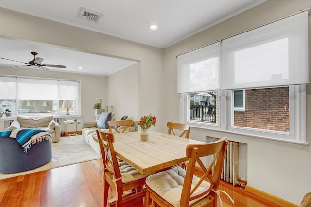 dining area with light wood-type flooring, crown molding, ceiling fan, and a healthy amount of sunlight