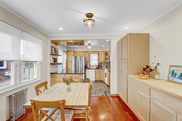 dining space with radiator heating unit, light hardwood / wood-style floors, and ornamental molding