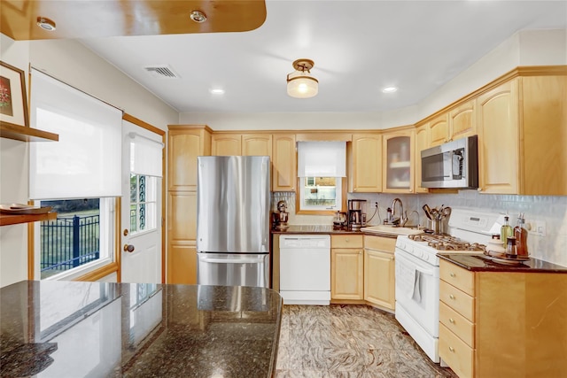 kitchen featuring dark stone countertops, light brown cabinets, stainless steel appliances, and sink