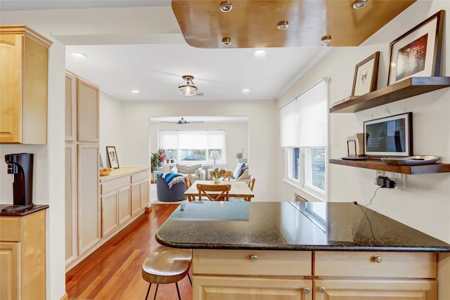 kitchen featuring light brown cabinetry, light hardwood / wood-style flooring, and dark stone counters