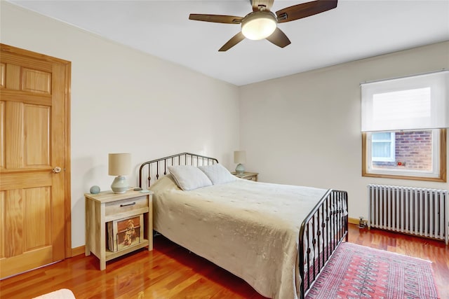 bedroom with ceiling fan, wood-type flooring, and radiator heating unit