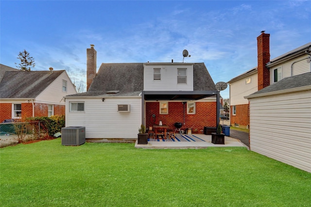 rear view of house with a wall unit AC, central AC, a yard, and a patio