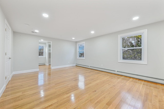 empty room with light hardwood / wood-style flooring and a baseboard heating unit