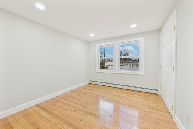 unfurnished bedroom featuring light hardwood / wood-style floors and a baseboard heating unit