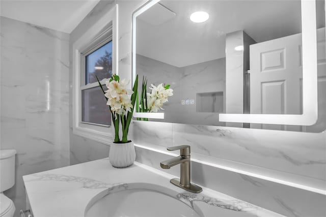 bathroom with vanity, tile walls, and toilet