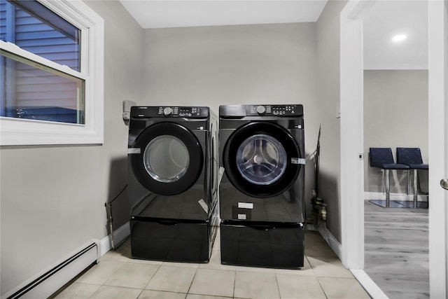 laundry room featuring a baseboard heating unit, light tile patterned floors, and washer and dryer