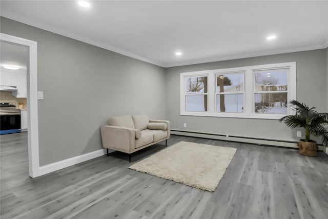 living area with crown molding, light hardwood / wood-style flooring, and a baseboard heating unit