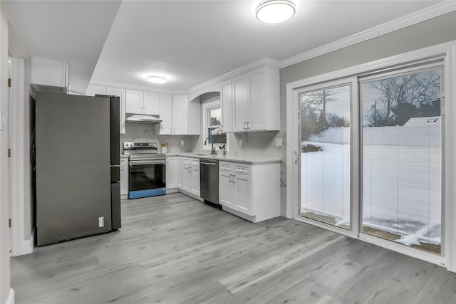 kitchen with sink, light hardwood / wood-style flooring, appliances with stainless steel finishes, ornamental molding, and white cabinets