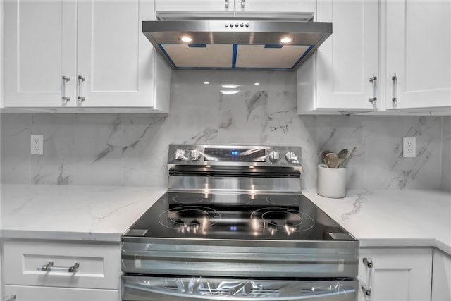 kitchen featuring backsplash, light stone countertops, stainless steel electric range, and white cabinets