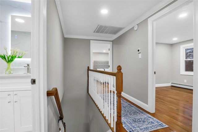 hall with crown molding, sink, hardwood / wood-style floors, and baseboard heating