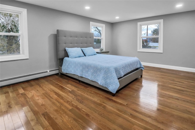 bedroom with hardwood / wood-style flooring and a baseboard heating unit