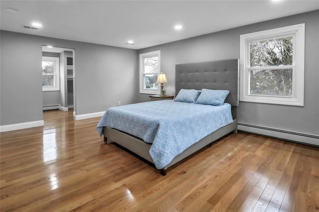 bedroom featuring hardwood / wood-style floors and a baseboard heating unit