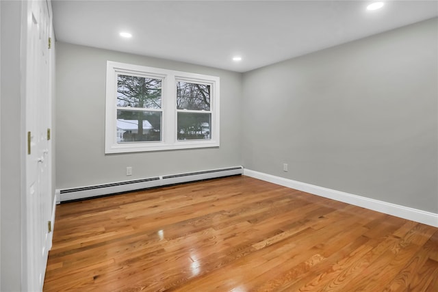 spare room featuring a baseboard heating unit and hardwood / wood-style floors