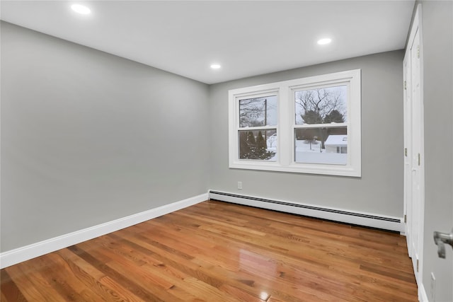 spare room with a baseboard heating unit and light hardwood / wood-style floors