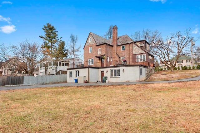 back of house with a yard, a sunroom, and a balcony