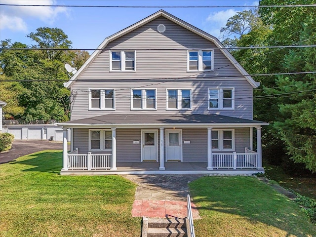 view of front property with a garage, covered porch, an outbuilding, and a front lawn