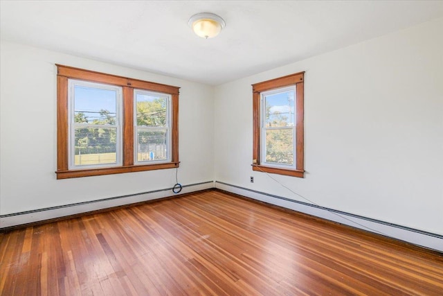 unfurnished room with wood-type flooring and a baseboard heating unit