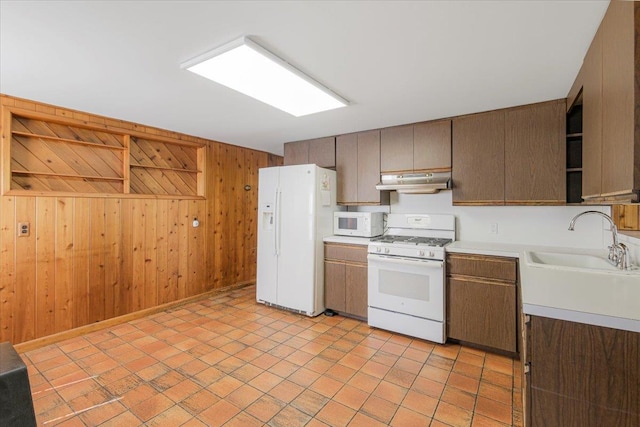 kitchen with white appliances, sink, and wooden walls