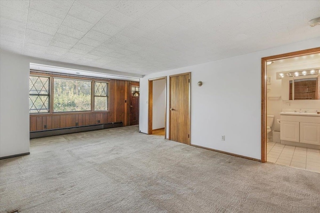 unfurnished room with light carpet, sink, and a baseboard radiator