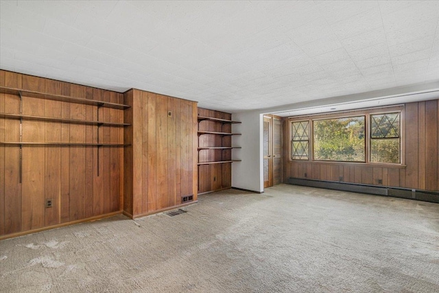 unfurnished living room featuring wood walls, light colored carpet, and a baseboard radiator