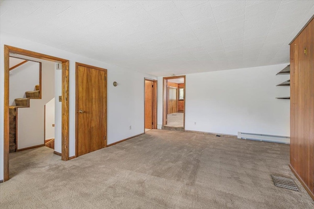 carpeted spare room with a baseboard heating unit