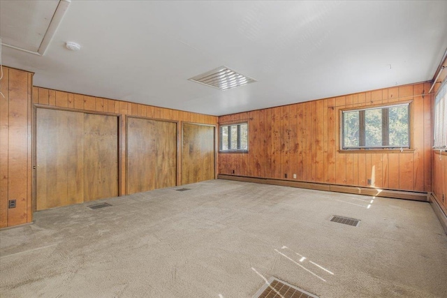 spare room with light carpet, wooden walls, and a baseboard heating unit