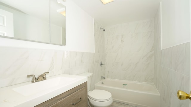 full bathroom featuring vanity, tiled shower / bath combo, toilet, and tile walls