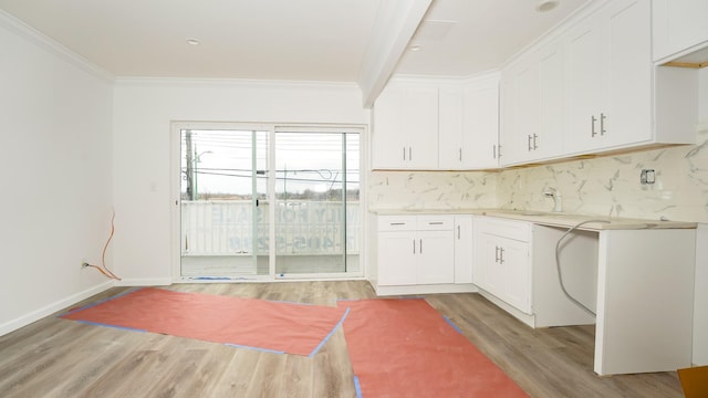 kitchen featuring white cabinets, sink, ornamental molding, and backsplash