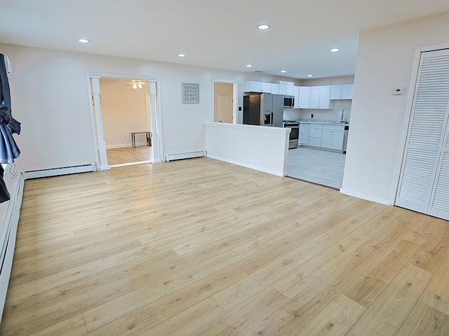 unfurnished living room featuring a baseboard radiator, recessed lighting, a baseboard heating unit, a sink, and light wood-type flooring