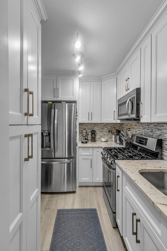 kitchen featuring white cabinetry, appliances with stainless steel finishes, light stone countertops, light hardwood / wood-style flooring, and tasteful backsplash