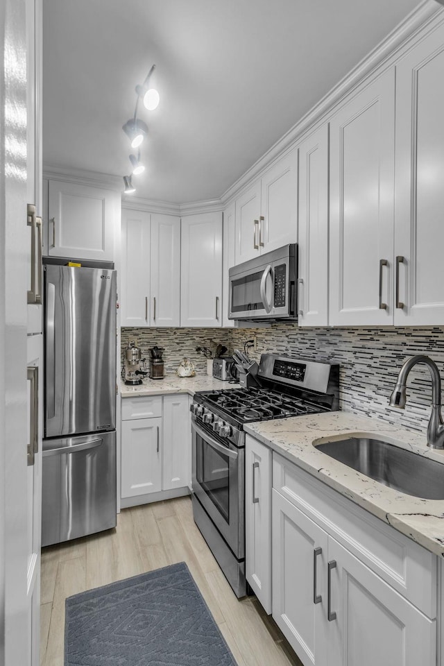 kitchen with sink, white cabinets, light stone counters, tasteful backsplash, and appliances with stainless steel finishes