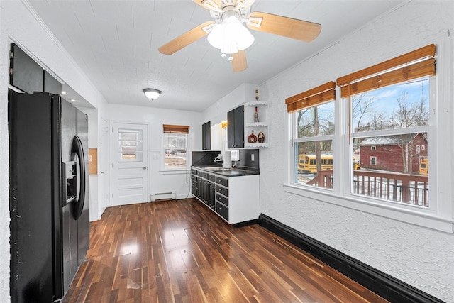 kitchen with sink, ceiling fan, baseboard heating, dark hardwood / wood-style floors, and black fridge