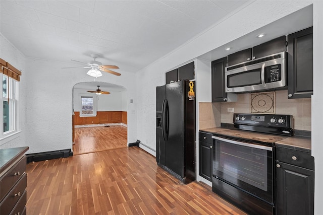 kitchen featuring dark wood-type flooring, ceiling fan, baseboard heating, tasteful backsplash, and black appliances