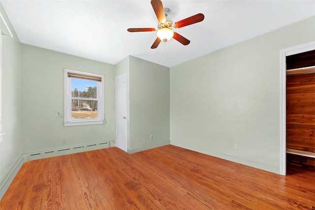 spare room featuring wood-type flooring, a baseboard heating unit, and ceiling fan