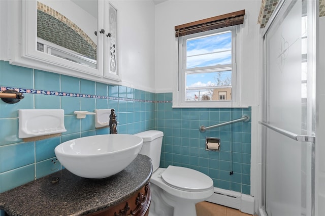 bathroom with sink, tile walls, baseboard heating, and toilet