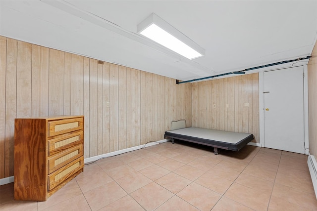 interior space with tile patterned flooring, a baseboard heating unit, and wood walls